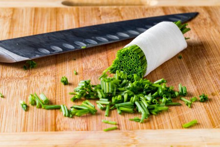 Photo for Close up view of Freshly chopped chives on a cutting board with a sharp knife. - Royalty Free Image