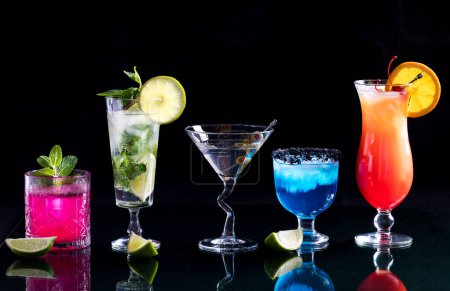 Téléchargez les photos : Une rangée de cocktails aux couleurs vives sur une table en verre, sur fond noir. - en image libre de droit
