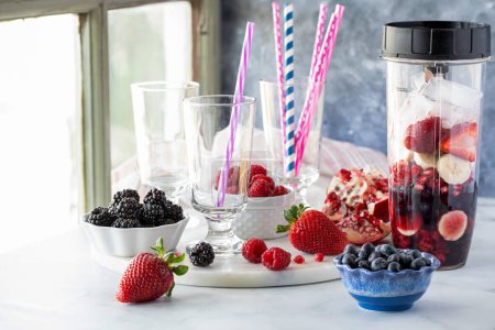 A blender container filled with ingredients used to make a mixed berry smoothie, ready for mixing.