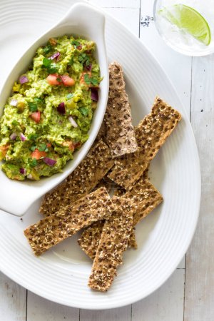 Rustic multi grain cracker sticks served with homemade guacamole for dipping.