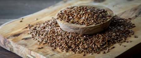 Photo for A narrow close up view of a small wooden bowl overflowing with whole organic flax seeds. - Royalty Free Image