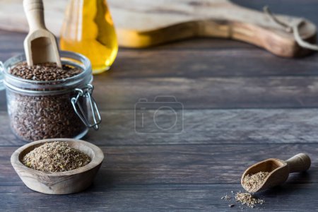 Photo for Ground and whole flax seeds with a bottle of flax seed oil and a cutting board in behind. - Royalty Free Image