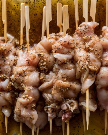 Photo for Close up view of raw chicken marinading on bamboo skewers. - Royalty Free Image