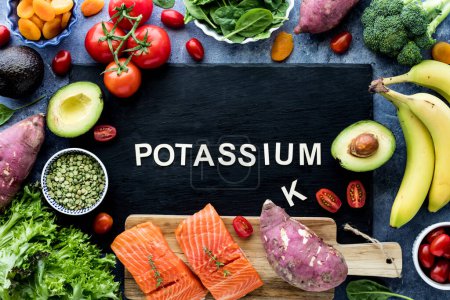 Photo for Above view of the word Potassium on a black slate board surrounded by foods high in potassium. - Royalty Free Image