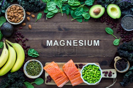 Photo for Healthy foods forming a border with the word Magnesium in the middle, on a wooden table. - Royalty Free Image