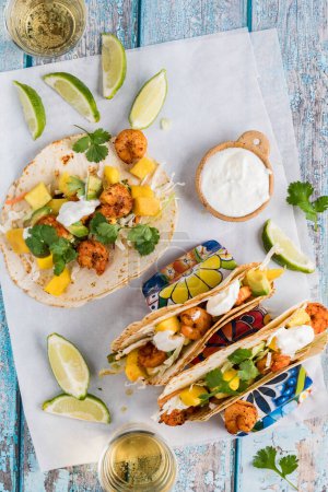 Photo for Top down view of loaded spicy shrimp tacos with cilantro and lime yogurt sauce, ready for eating. - Royalty Free Image