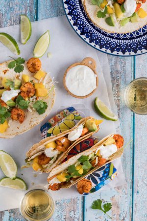 Photo for Loaded spicy shrimp tacos topped with lime yogurt sauce and cilantro, ready for eating. - Royalty Free Image