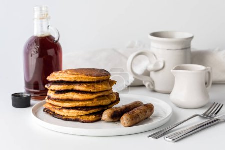 Photo for A stack of delicious sweet potato pancakes served with maples syrup and sausages. - Royalty Free Image