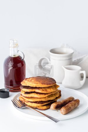 Photo for A stack of freshly made sweet potato pancakes served with sausages for breakfast. - Royalty Free Image