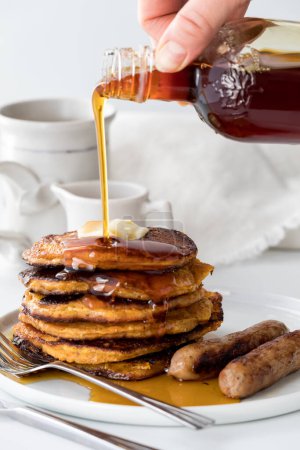 Photo for A hand pouring syrup onto a fresh homemade stack of sweet potato pancakes. - Royalty Free Image