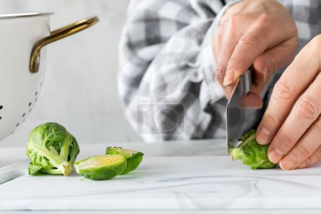 Photo for Hands preparing raw brussel sprouts for cooking. - Royalty Free Image