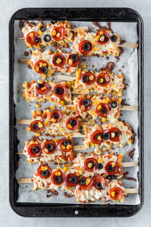 Oben Blick auf Pizza-Pasta-Spieße auf einem Backblech, heiß aus dem Ofen.