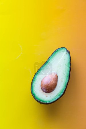 A close up of a sliced avocado against a yellowy orange background. 