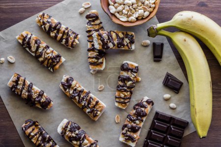 Tiefgefrorene Bananen-Erdnussbutter-Häppchen mit dunkler Schokolade auf einem Stück Pergamentpapier geträufelt.