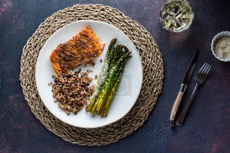 A plate of cooked salmon with parmesan asparagus and a side of quinoa with lentils.