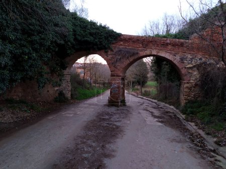 Foto de Roman aqueduct in Cerdanyola del Valles, province of Barcelona, Catalonia, Spain, located in the middle of a current road and in a poor state of preservation. - Imagen libre de derechos
