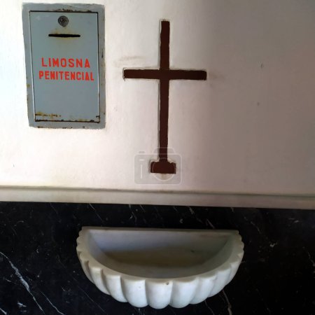Foto de Font to cross yourself with wooden crucifix and mailbox for alms in a catholic church in Andalusia in southern Spain, - Imagen libre de derechos