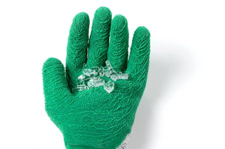 Photo for View from above of green very high cut resistance gloves covered with crinkled latex and glass shards on white background. - Royalty Free Image