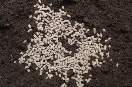 Photo for View from above of heap granulated chicken manure on black soil. Eco home gardening concept. - Royalty Free Image
