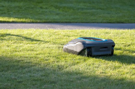 Foto de Segadora robótica inteligente cortando hierba en un día soleado - Imagen libre de derechos