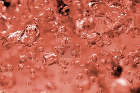 A closeup shot highlighting the intricate details and movement of effervescent bubbles suspended in a fluid with a warm color palette.