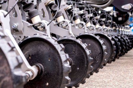 Close up of agricultural machinery, focusing on metal discs aligned in a row, showcasing agricultural equipment parts.