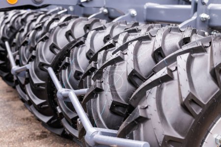 Detalle de disparo que muestra una alineación de neumáticos de tractores grandes y pesados con patrones de banda de rodadura, que representan el equipo de la industria agrícola.