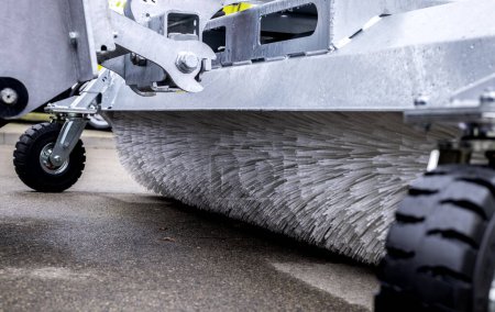 This image features a detailed close-up of a modern street sweeper's brush system, focusing on its design and functionality while cleaning urban roads.