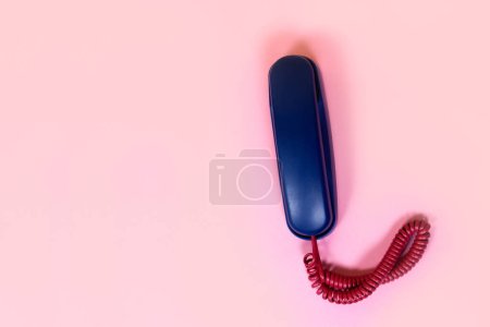 Photo for Top view of blue telephone with red cord on pink background - Royalty Free Image
