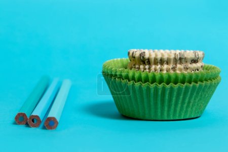 Photo for Green and white paper cups and blue crayons on blue background - Royalty Free Image