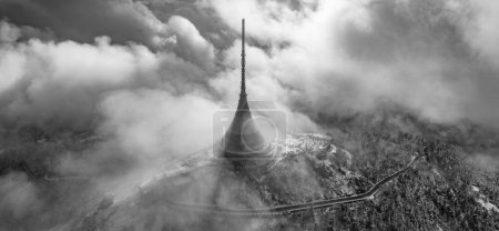Jested mountain with modern hotel and TV transmitter on the top, Liberec, Czech Republic. Building in clouds. Aerial view from drone.. Black and white image.