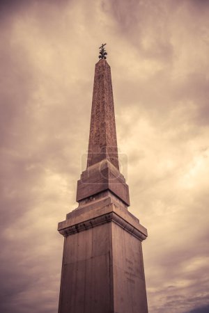 El antiguo Obelisco de Sallustiano se eleva majestuosamente, sus jeroglíficos visibles contra un cielo dramático, lleno de nubes, evocando la grandeza histórica de los romanos. Roma, Italia