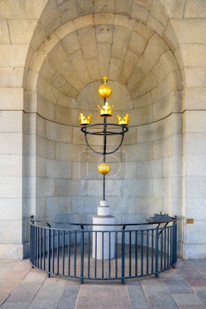 Le symbole des trois couronnes, emblème national de la Suède, se trouve dans une niche voûtée au musée de la couronne de Stockholm, entouré d'une rampe de protection..