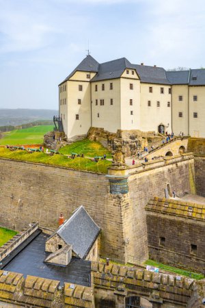 Los visitantes exploran las murallas históricas de la fortaleza de Konigstein en Sajonia, bajo un cielo nublado. Alemania