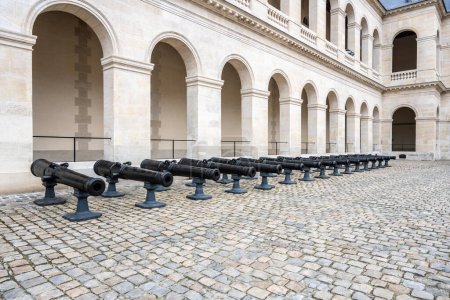 Rangée de vieux canons exposés aux Invalides historiques de Paris, symbolisant le passé militaire de la France.