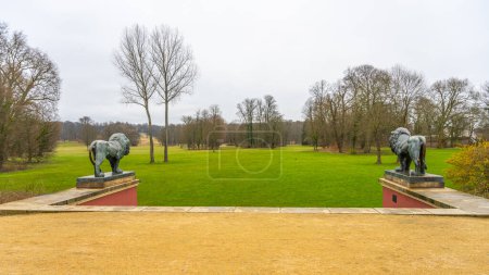 Mit Blick auf einen saftig grünen Rasen, flankiert von steinernen Löwenstatuen im renommierten Park von Bad Muskau. Sachsen, Deutschland