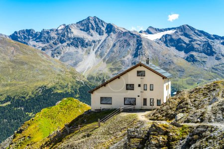 Nestled in the Italian Alps, the Tabaretta Hut offers a panoramic view of mountains around Ortles, basking under a clear blue sky on a bright sunny day.