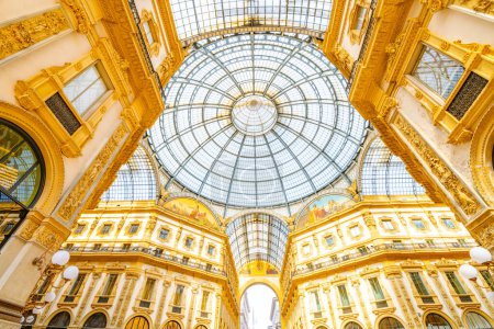 An exquisite capture of the Galleria Vittorio Emanuele II in Milan, Italy. The image showcases the intricate glass dome ceiling, surrounded by ornate golden architecture, reflecting the grandeur of