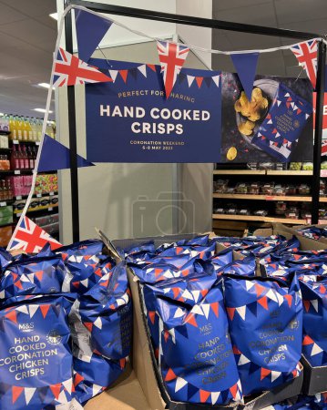 Téléchargez les photos : Des chips de couronnement cuites à la main sont exposées sur les étagères du supermarché MarkSpencer à Londres - avril 2023. Marchandises commémorant le couronnement du roi Charles III. - en image libre de droit