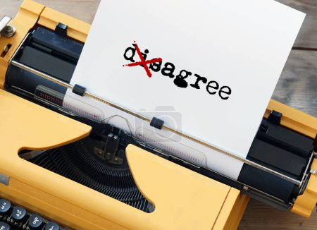 A yellow typewriter has the word agree disagree crossed out. High quality photo