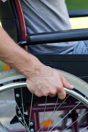 Disabled man using his wheel chair in park closeup. High quality photo