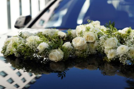 Blumenhochzeitsdekoration auf der Motorhaube eines Autos - Blumenschmuck. Hochwertiges Foto
