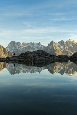 Photo for Silhouette of Man, Mountains and Reflection in Lac Blanc Lake at Sunset. Golden Hour. French Alps, France - Royalty Free Image