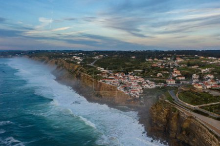 Weiße Häuser von Azenhas do Mar Village in Portugal bei Sonnenuntergang, Klippen und Wellen des Atlantiks. Luftaufnahme.