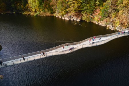 Téléchargez les photos : Aire de loisirs près du château de Grodno à Zagorze, Pologne. Paysage d'automne magnifique avec des montagnes couvertes de forêt, rivière et pont pour les gens sur elle - en image libre de droit