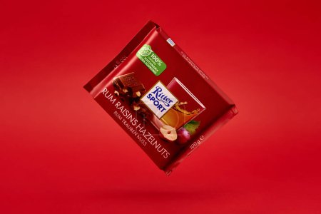 Photo for Flying bar of Ritter Sport chocolate. Rum raisins haselnuts flavor chocolate on red background. Wroclaw, Poland - December 28, 2022 - Royalty Free Image