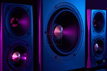 Photo for Two sound speakers and subwoofer on dark background with neon lights. Set for listening music. Audio equipment - Royalty Free Image