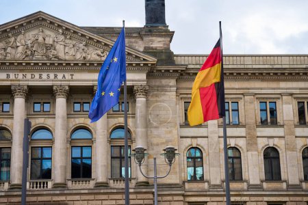 Nationalflagge Deutschlands und Flagge der Europäischen Union flattern im Wind vor dem Hintergrund des Bundestags-Gebäudes. Regierungsgebäude in Berlin