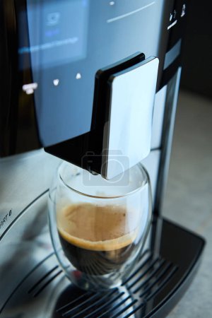 Foto de Un expreso recién hecho por la mañana. Cafetera con café recién hecho en taza de vidrio. Electrodomésticos de cocina - Imagen libre de derechos