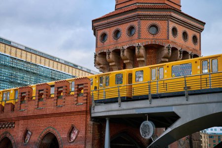Yellow train travels across a historic red brick bridge in Berlin